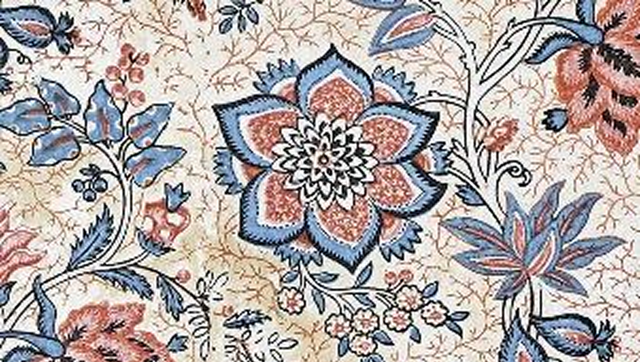 Motif floral ancien en bleu et rose sur fond craquelé, typique des papiers peints historiques exposés au Musée du Papier peint.